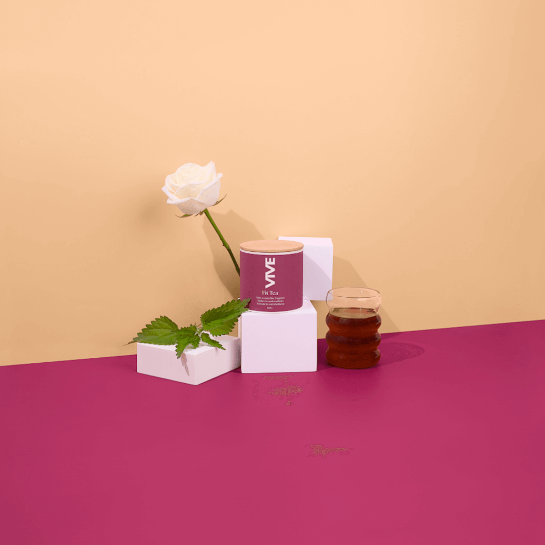 Fit Tea infusion displayed with a rose, herbal leaves, and a glass teacup on vibrant colored background.