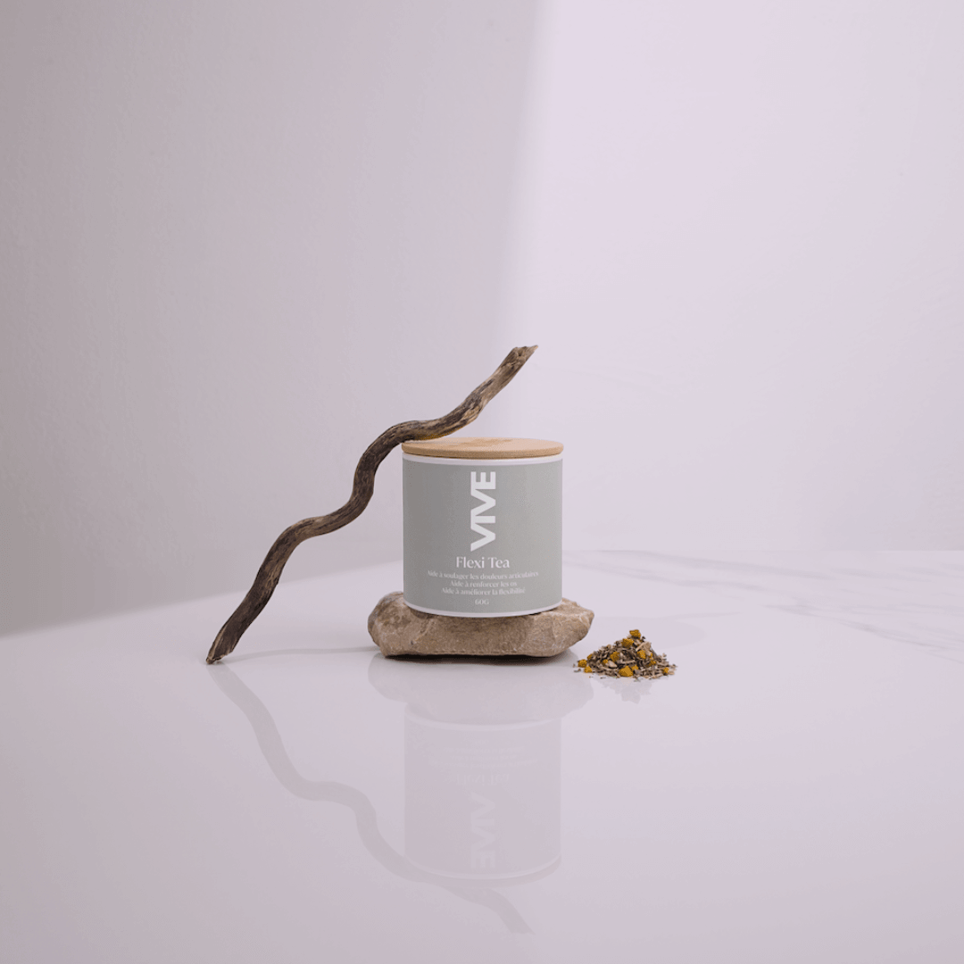 Pot de Flexi Tea sur un support en pierre, avec des plantes séchées, symbolisant une infusion pour articulations saines.